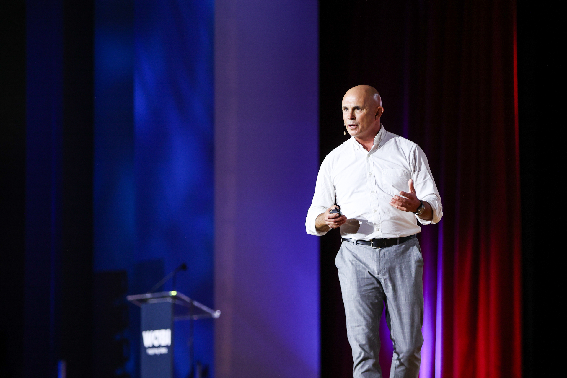 Doug Manuel speaking on stage in a white shirt